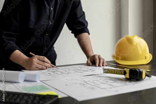 The architect and engineer are drawing up the drawings of the house according to the project received. He works in his office, he does the design according to the needs of the clients.