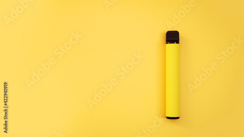 Yellow disposable electronic cigarette on bright yellow background photo