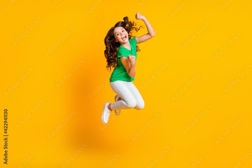 Full size photo of happy excited screaming happy smiling girl jumping in victory triumph isolated on yellow color background Full size photo of happy excited screaming happy smiling girl jumping in victory triumph isolated on yellow color background