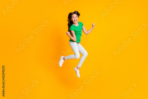 Full size photo of happy excited smiling crazy girl jumping in victory success triumph isolated on yellow color background
