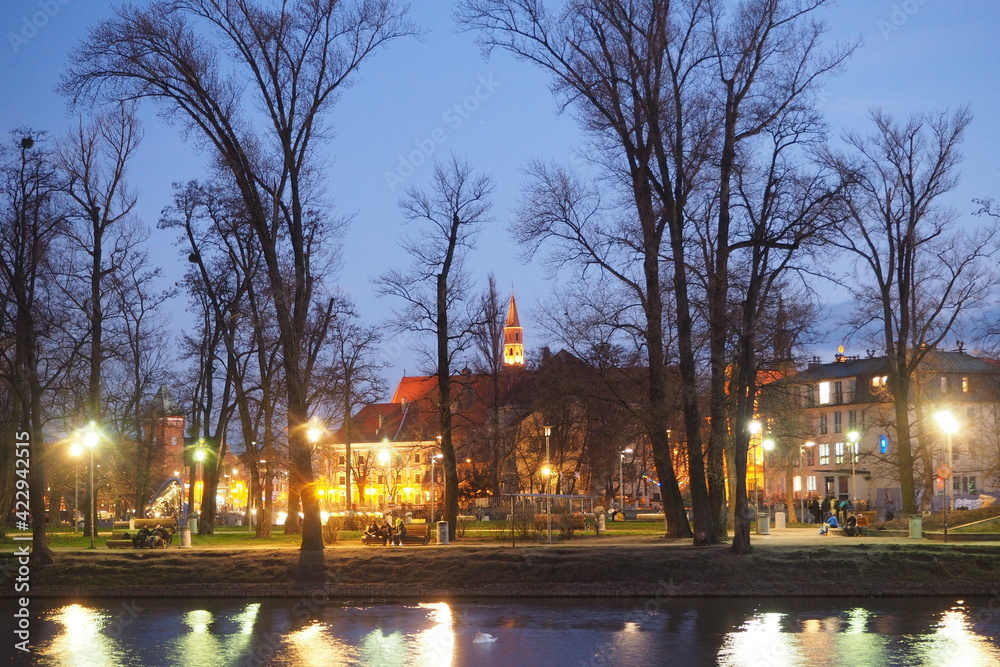 Widok na park przez rzekę we Wrocławiu wieczorem, Polska