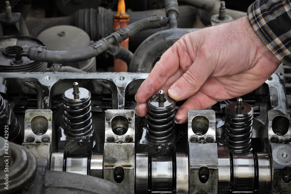 Car mechanic fixing modern diesel engine, closeup of hand removing injectors from cylinder head Car mechanic fixing modern diesel engine, closeup of hand removing injectors from cylinder head
