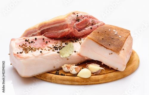 raw pork meat and lard with salt, spices and garlic on a cutting board, white background