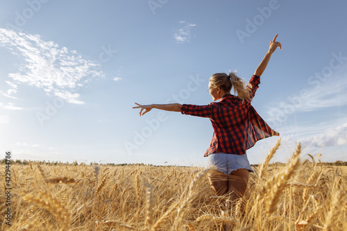 Silhouettes of a slender young woman with outstretched arms. A woman stands in a field of golden wheat. The atmosphere is summer and joyful. High quality photo