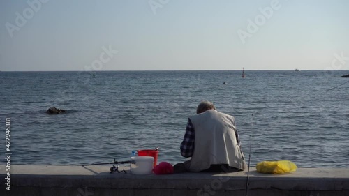 Αn old man is fishing in the calm sea .Τhe plan is fixed. photo