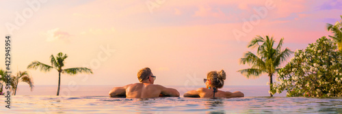 Panoramic photo of couple in pool enjoying tropical vacation by sunset