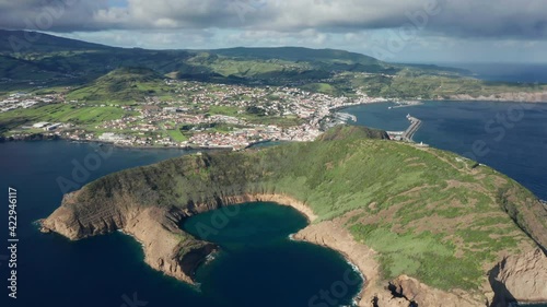 Drone flying over Monte de Guia volcanic mountain in atlantic ocean, Faial Island, Azores, Portugal, Europe. Picturesque landscape with green area and Horta city buildings, 4k footage