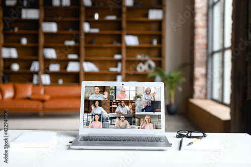 Online meeting of diverse work team, video call, video conference. App for video connection on laptop screen in office, profiles of several people, office staff on the monitor photo