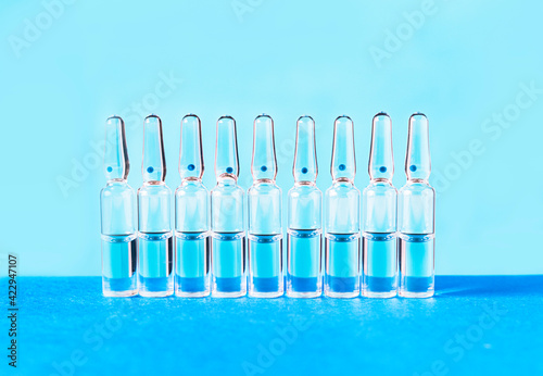Medical ampoules for injection on a blue background. Scattered glass ampoules with medicine on the table. Medicines and disease treatment