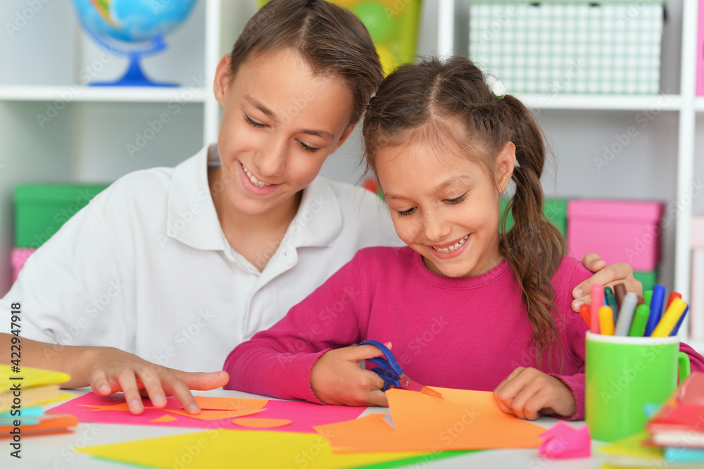 Cute brother and sister cutting colorful paper Cute brother and sister cutting colorful paper