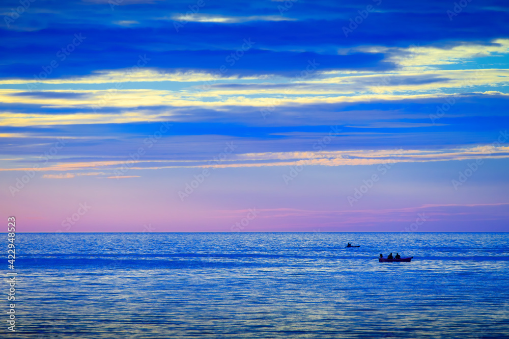 two boats on blue sea with twilight cloudy sky