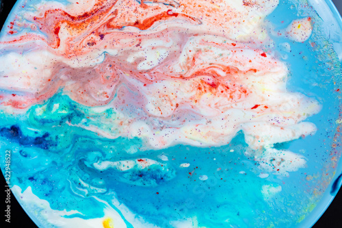 The background is acrylic soft blue with pink and sparkles. Colorful marble texture. Fluid liquid marble. Art picture. Avant-garde creativity.