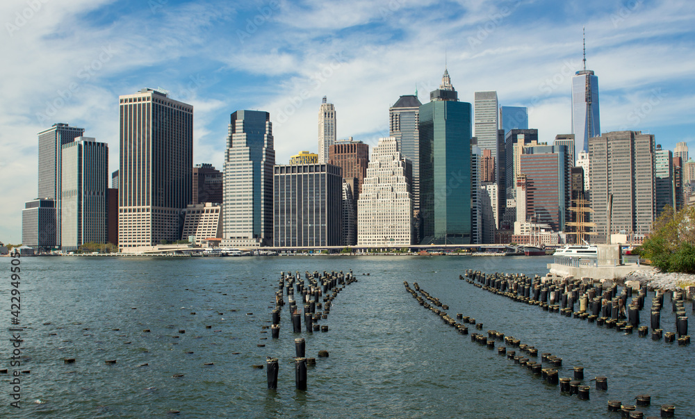 Old pier pylons and Downtown Manhattan, New York City.