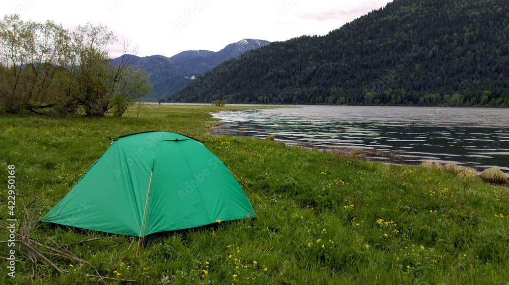 The tent of tourists stands on the coast of a mountain lake.