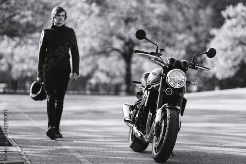 Man with helmet in his hand goes to the motorcycle. Black and white photography. Biker concept.