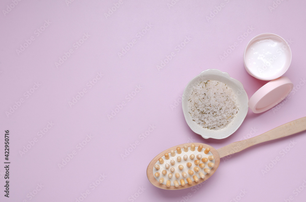 Top view of bowl of skin renewing scrub, lotion and dry wooden brush on the pink surface.Empty space