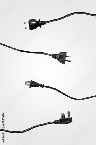 Four international black power plugs, isolated on light gray studio background