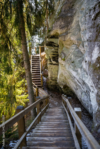 tourist trail with wooden pathwalk and stairs near sandstone cliffs. river gauja in Latvia. The cliff of Sietiniezis photo