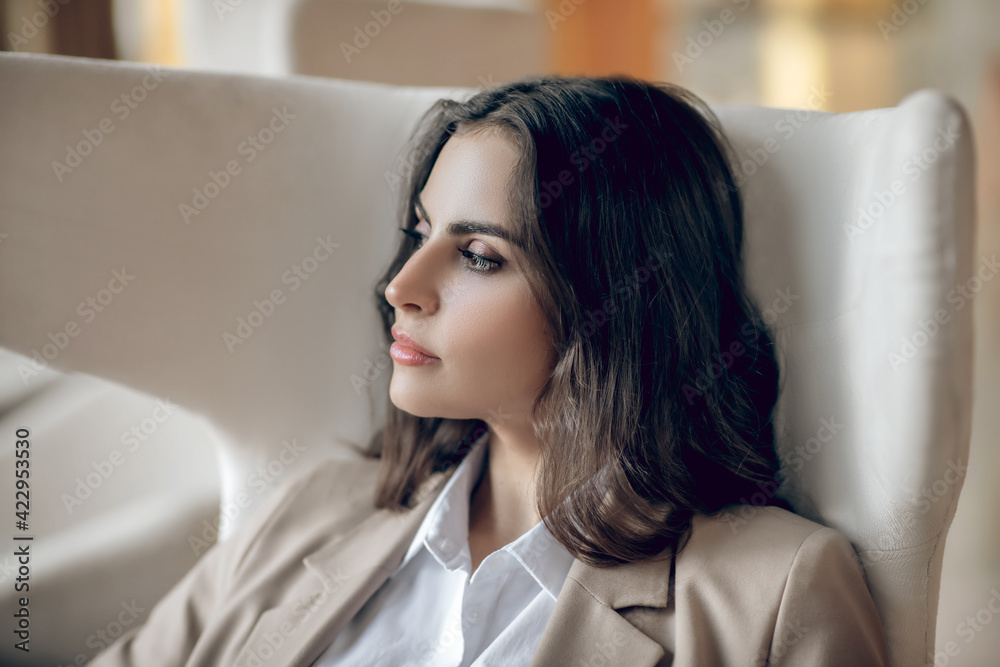 Pretty businesswoman sitting in the armchair and looking serious Pretty businesswoman sitting in the armchair and looking serious