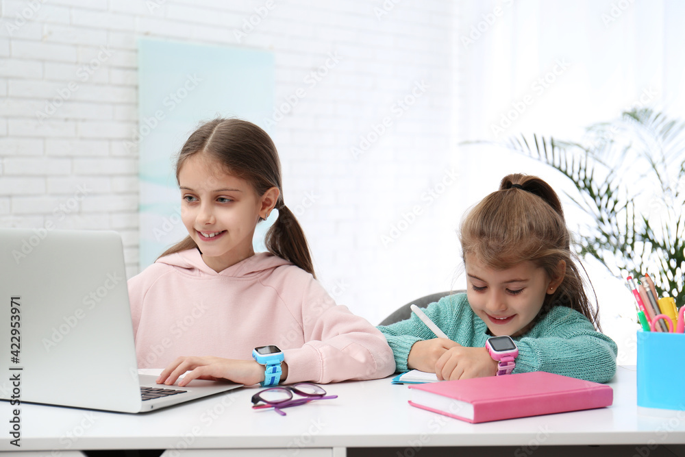 Girls with stylish smart watches at table indoors Girls with stylish smart watches at table indoors