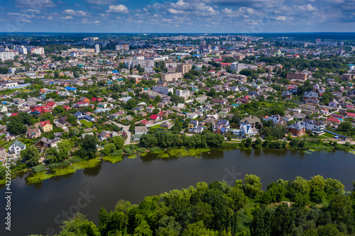 Beautiful summer top view of the city. Roofs of houses, river, trees with green leaves.