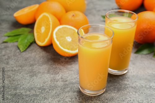 Delicious orange juice and fresh fruits on grey table. Space for text
