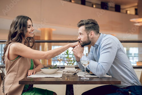 A couple sitting at the table in the restaurant and man kissing womans hands