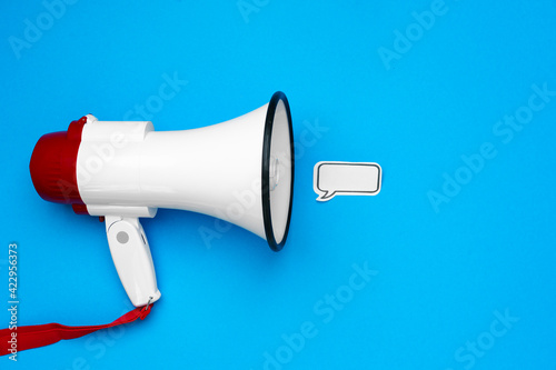 Electronic megaphone and speech bubble on blue background