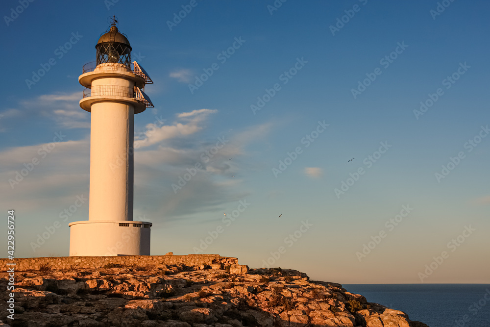 lighthouse on Formentera during sunset, beautiful blue orange sky with seagulls flying lighthouse on Formentera during sunset, beautiful blue orange sky with seagulls flying