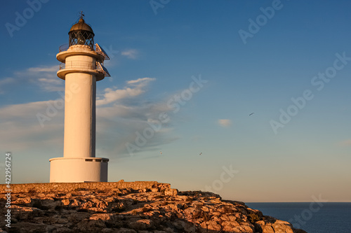 lighthouse on Formentera during sunset, beautiful blue orange sky with seagulls flying