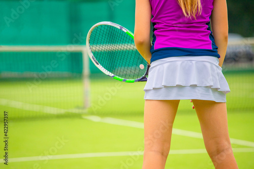 a girl in a pink t shirt and white tennis skirt plays on a grass tennis court