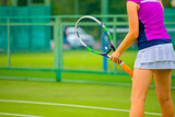 a girl in a pink t shirt and white tennis skirt plays on a grass tennis court
