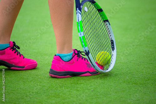 close-up of a tennis player's feet lifting a tennis ball from the court
