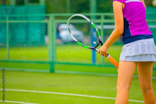 a girl in a pink t shirt and white tennis skirt plays on a grass tennis court © Павел Мещеряков