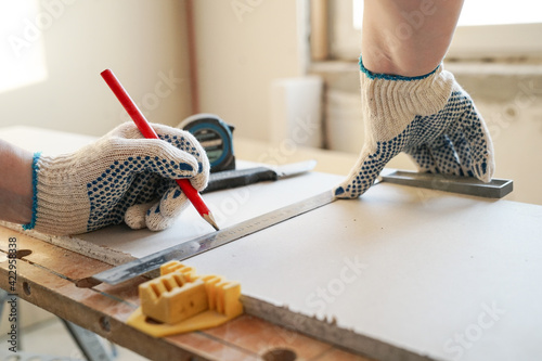 Builder measures and marks drywall sheet