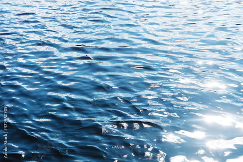 Ripples on lake water. Sunlight reflecting in water. Sun shining by the lake. Ocean wave background. Wavy pond texture. Messy water flow. Blue water surface background. Sky reflection pattern.