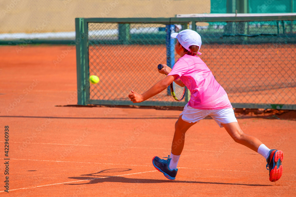 a boy in a pink t-shirt and white shorts is playing tennis