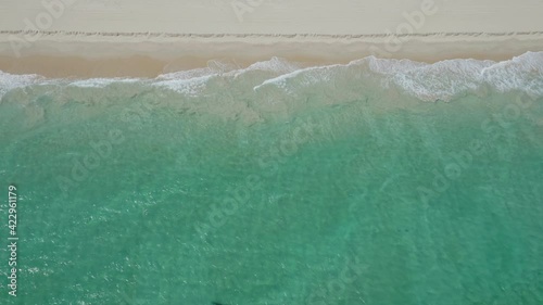 Waves washing ashore on a sandy beach in Perth, Western Australia as seen from a bird's eye view.