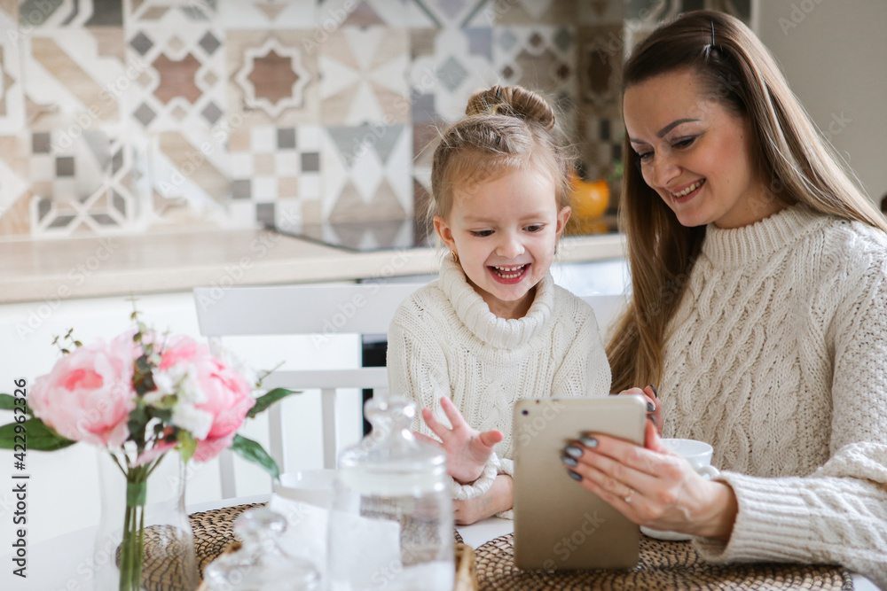Smiling mother takes selfie with cute daughter on tablet, happy young mom laughing makes photo with daughter at home, single mom and adopted children playing fun with phone Smiling mother takes selfie with cute daughter on tablet, happy young mom laughing makes photo with daughter at home, single mom and adopted children playing fun with phone