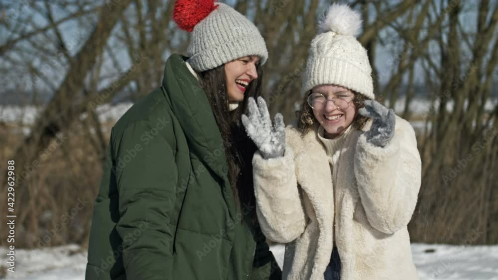 Cute teenage girl and her older sister or mom are playing with snow during a winter walk. Cute teenage girl and her older sister or mom are playing with snow during a winter walk.