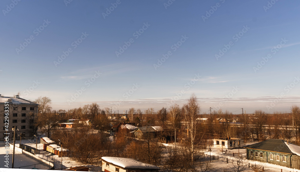The countryside in winter weather, blue clear skies, railway tracks, view from above, visible private houses, village life, village in winter.
