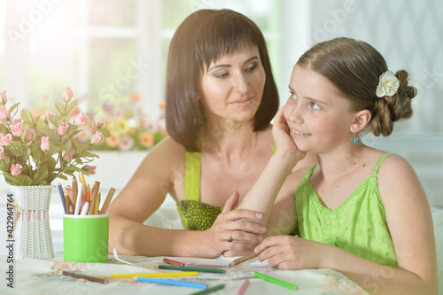 girl with mother drawing at the table at home