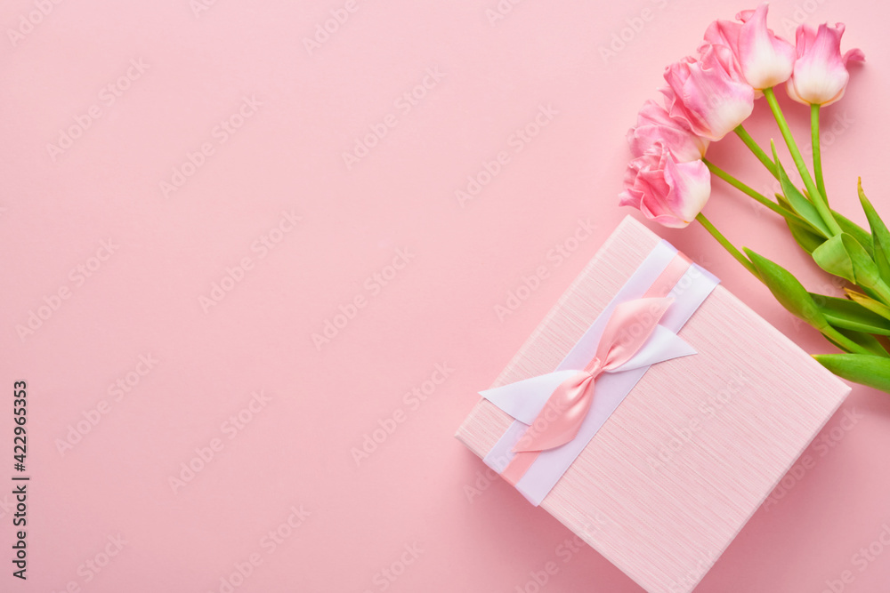 Easter greeting card with easter gingerbread eggs gift box and tulip flowers over pink background. Top view flat lay with copy space Easter greeting card with easter gingerbread eggs gift box and tulip flowers over pink background. Top view flat lay with copy space