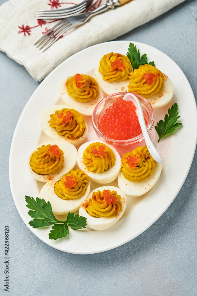 Stuffed eggs with red caviar and paprika on plate for appetizer easter table, top view, copy space. Traditional dish for Happy Easter holiday.