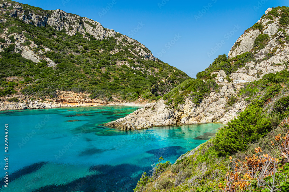Porto Timoni beach on Corfu island in Greece. Beautiful view of green mountains, clear sea water, secluded Pirates bay and hidden stony beach. Famous destination for summer vacation and hiking