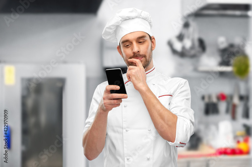 male chef with smartphone at restaurant kitchen