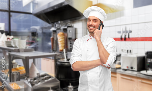 happy smiling male chef calling on smartphone