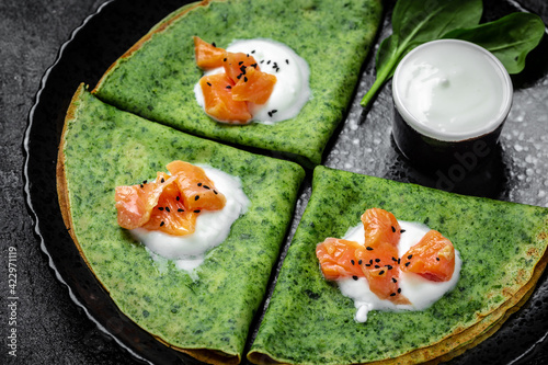 Green spinach crepes or pancakes with smoked salmon and sour cream. vegetarian food, banner, menu recipe top view