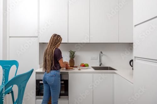 Side view of young female preparing healthy sandwiches for breakfast in light modern home kitchen