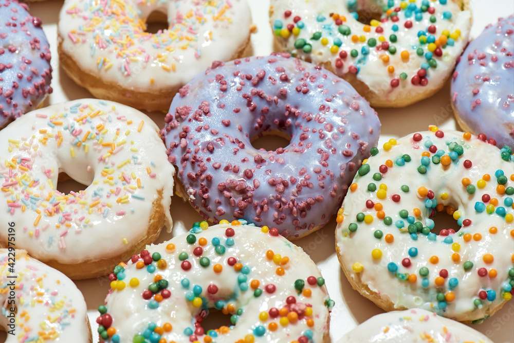 Sugary food. Close up shot of assorted round glazed donuts with colorful sprinkles, top view